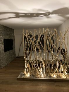 an artistic sculpture made out of branches in a room with wood flooring and white walls