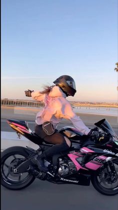 a woman riding on the back of a pink motorcycle