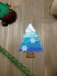 a christmas tree made out of felt sitting on top of a wooden table next to a ball of yarn