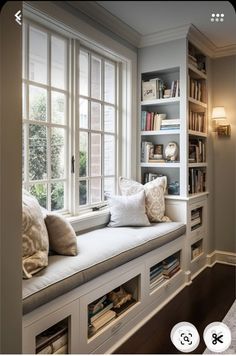 a window seat with bookshelves and pillows on it