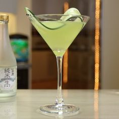 a green drink sitting on top of a table next to a bottle