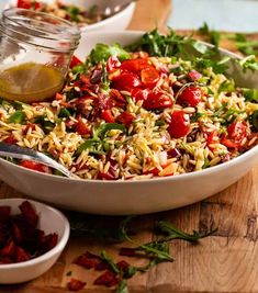 a salad with tomatoes, lettuce and other toppings in a bowl on a wooden cutting board