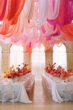 the tables are set with white linens and colorful streamers hanging from the ceiling