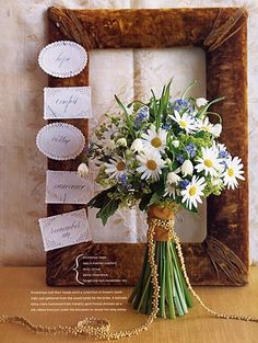 a bouquet of white and blue flowers sitting in front of a wooden frame on the wall