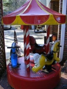 a merry go round carousel with horses on the front and side, next to a blue fire hydrant