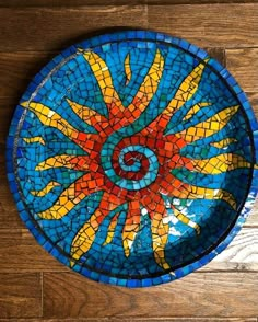 a blue and yellow plate sitting on top of a wooden floor