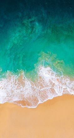 an aerial view of the ocean and beach with waves crashing on it's shore