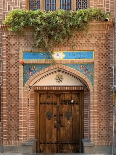 an entrance to a building with two wooden doors and green plants growing over the door