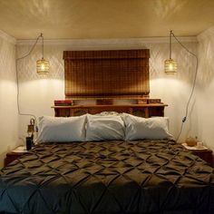 a bed with two lamps on either side of the headboard and an old fashioned dresser behind it