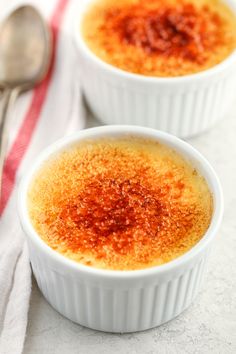 two small white bowls filled with food on top of a table next to a spoon