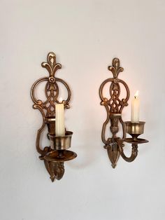 two wall sconces with lit candles on them