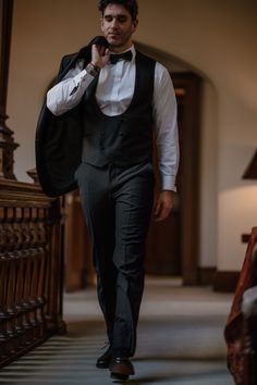 a man in a tuxedo is walking down the hall with his jacket on