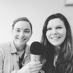 two women sitting next to each other holding microphones and smiling at the camera,