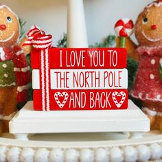 two gingerbread people are standing next to a sign that says i love you to the north pole and back