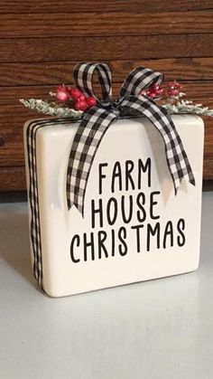 a white ceramic box with a black and red bow on it that says farm house christmas