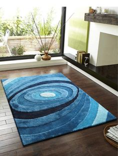 a blue area rug with an abstract design on the floor in front of a window