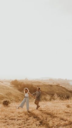 two people holding hands in the middle of a field