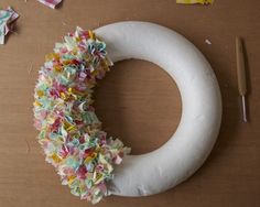 a wreath made out of toilet paper on a table next to scissors and other crafting supplies