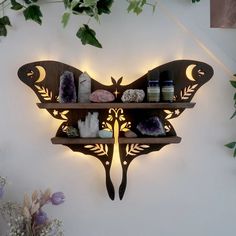 a butterfly shaped shelf with candles and other items on it