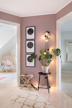 a living room with pink walls and pictures on the wall, plants in vases