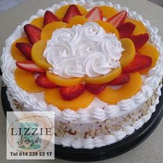 there is a cake with fruit on the top and frosting in the shape of flowers