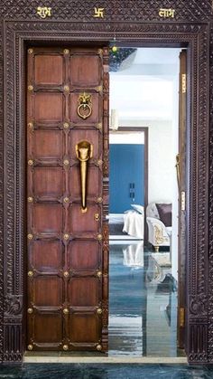 an ornate wooden door is open to the living room