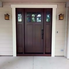 the front door to a house with two lights on each side and an entry way