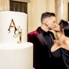 a bride and groom kissing in front of a white wedding cake with the letter j on it