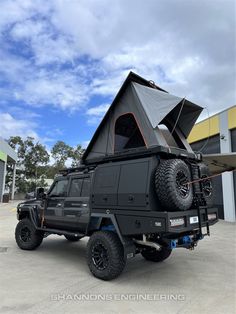 an off road vehicle parked in front of a building with a tent on the roof