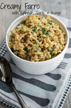 a white bowl filled with rice and spinach on top of a napkin next to a fork