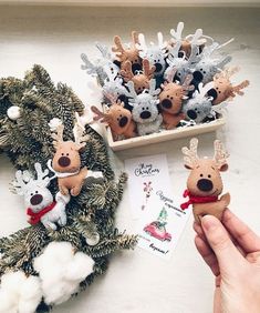 someone is holding some christmas decorations in front of the wreath and other ornaments on the table