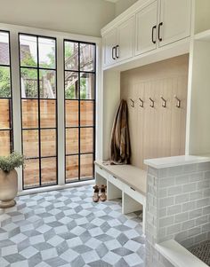 a white bench sitting in front of a window next to a potted plant on top of a tiled floor