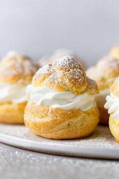 small pastries with icing and powdered sugar on a white plate, ready to be eaten