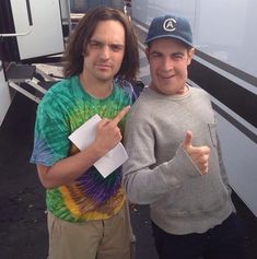 two men standing next to each other in front of a trailer giving the thumbs up