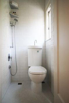 a white toilet sitting inside of a bathroom next to a shower head mounted on a wall