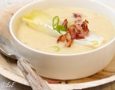 a white bowl filled with soup on top of a wooden plate