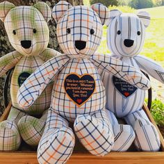 three teddy bears sitting next to each other in front of a tree with a heart on it