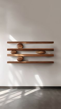 a wall mounted sculpture with wooden bowls on it's sides in an empty room