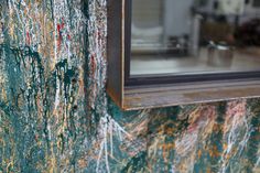 an old window frame is painted green and red with paint splattered on it