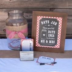 a table topped with a mason jar filled with candy next to a couple of cards