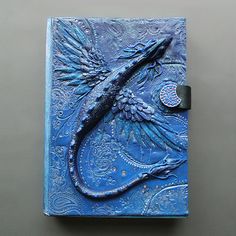 a blue book with an intricate design on the front and back cover that is shaped like a bird