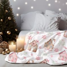 a bed covered in a blanket next to a lit christmas tree and two small candles