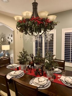 a dining room table set for christmas with place settings on the plates and centerpieces