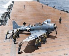 an old photo of men standing on the deck of an aircraft carrier with fighter jets