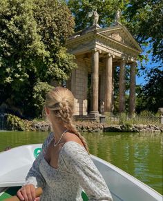 a woman sitting on top of a boat in front of a building with columns and pillars