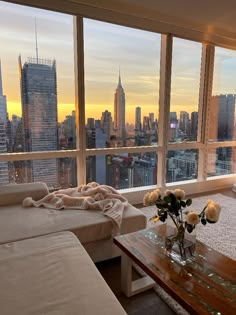 a living room filled with furniture and large windows overlooking the cityscape at sunset