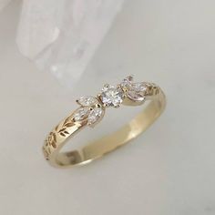 a yellow gold ring with three diamonds on it's side, sitting on a white surface