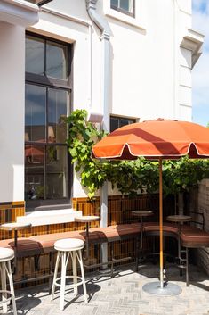 an orange umbrella sitting on top of a wooden table next to white chairs and tables