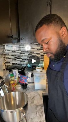 a man standing in front of a kitchen counter next to a mixing bowl and mixer