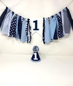 a blue and white birthday banner with a number one hanging from it's side